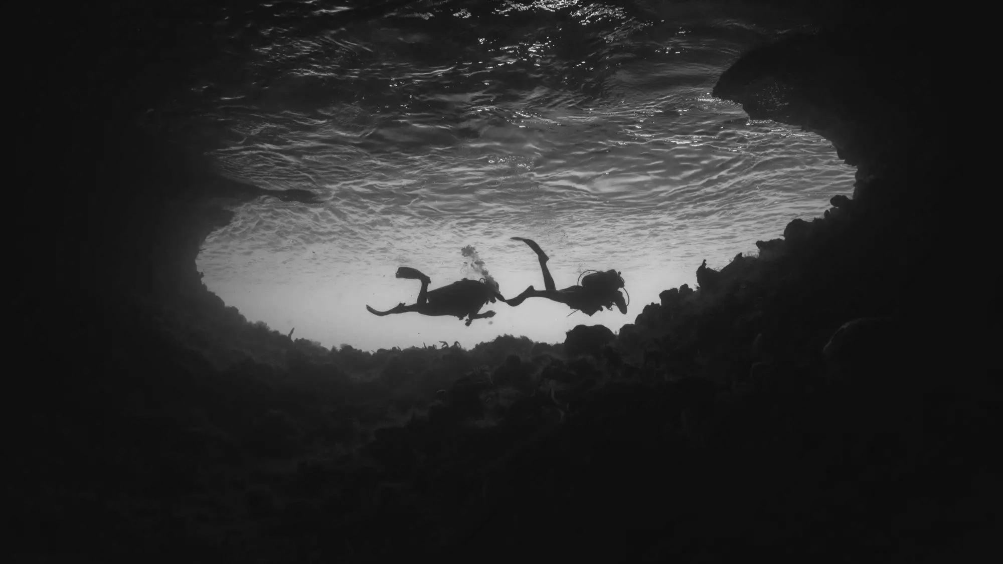 Divers swimming through a cave