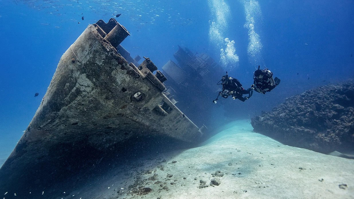 Divers swimming towards a wreck.