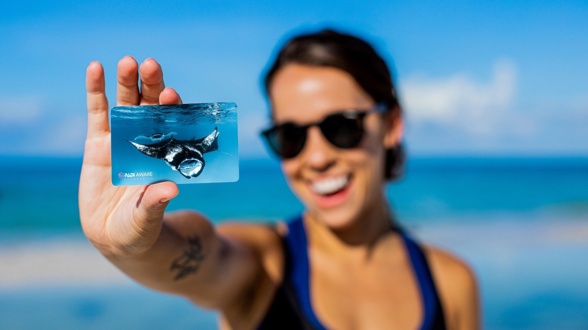 woman holding a PADI certification card to the sun light