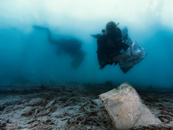 Two divers picking up litter in the ocean.