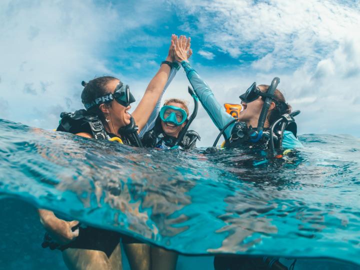 Scuba divers giving each other high fives in the ocean