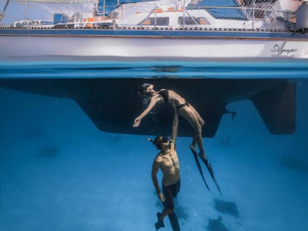 Rachel Moore and Josh Shankle known as Voyages of Agape with an incredible pose underwater near their boat
