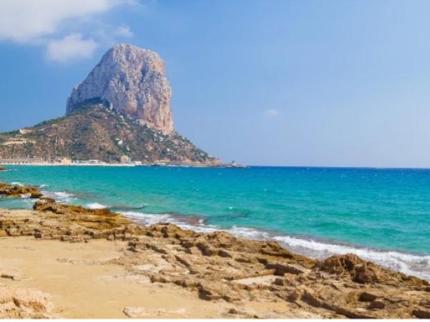 Beach shore with a huge boulder in the distance.