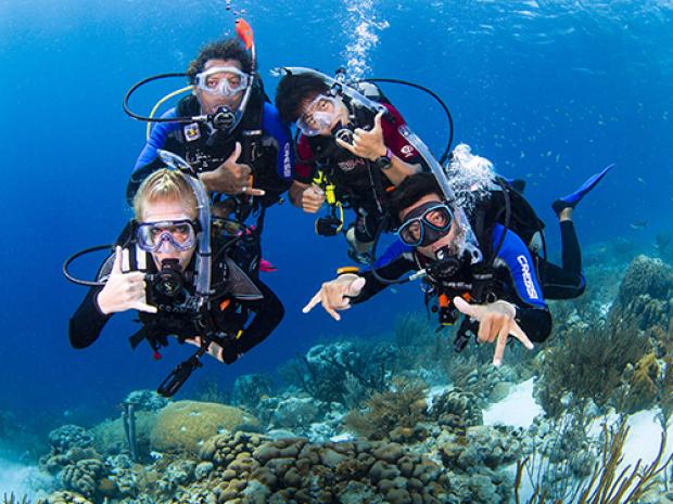 A family of divers posing for the camera underwater.