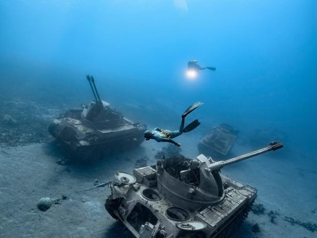 Diver discovering tank wrecks underwater