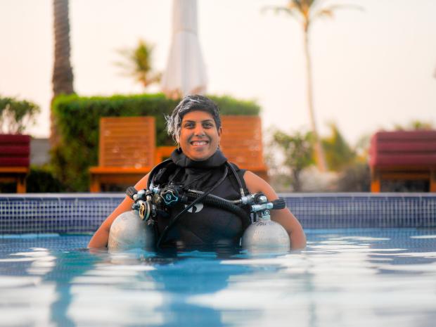PADI AmbassaDiver Sara Gojer smiling while in her scuba diving gear above water.