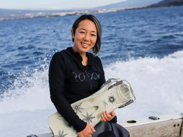 PADI AmbassaDiver Yumi Shirai smiling as she holds her flippers.