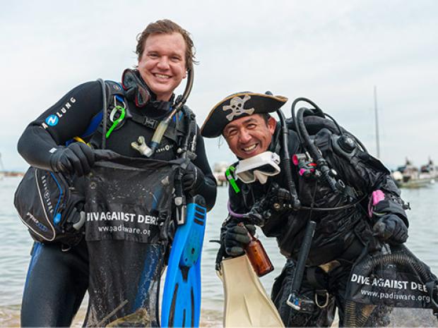 two divers showing their dive against debris shirts