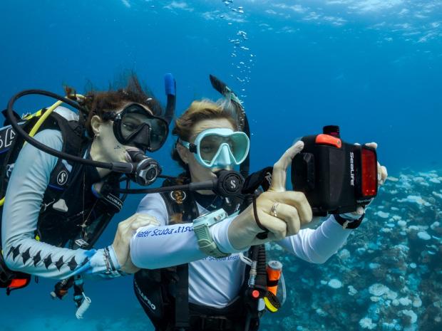 Two female divers holding cameras underwater