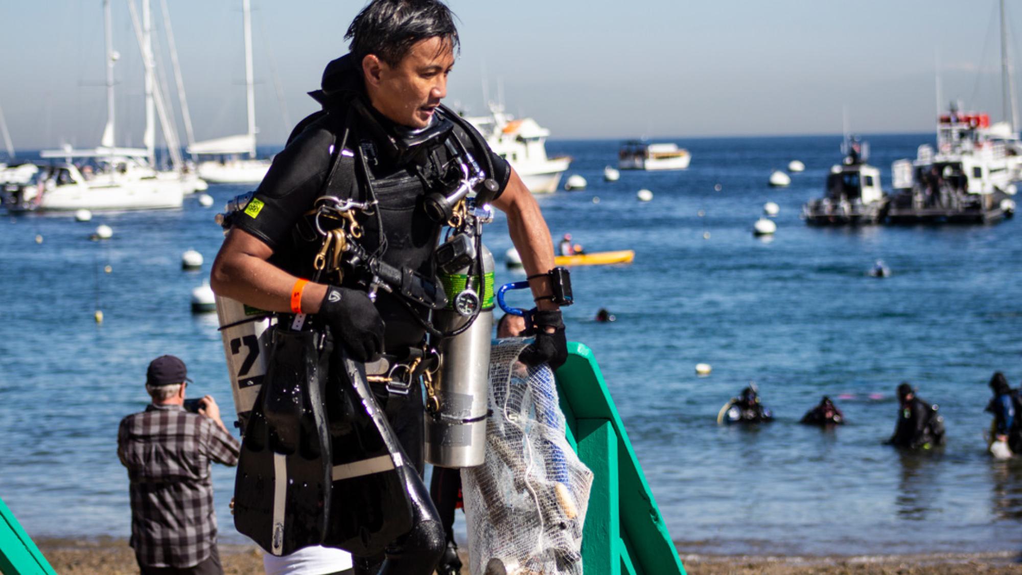 a diver carrying marine debris in mesh bag