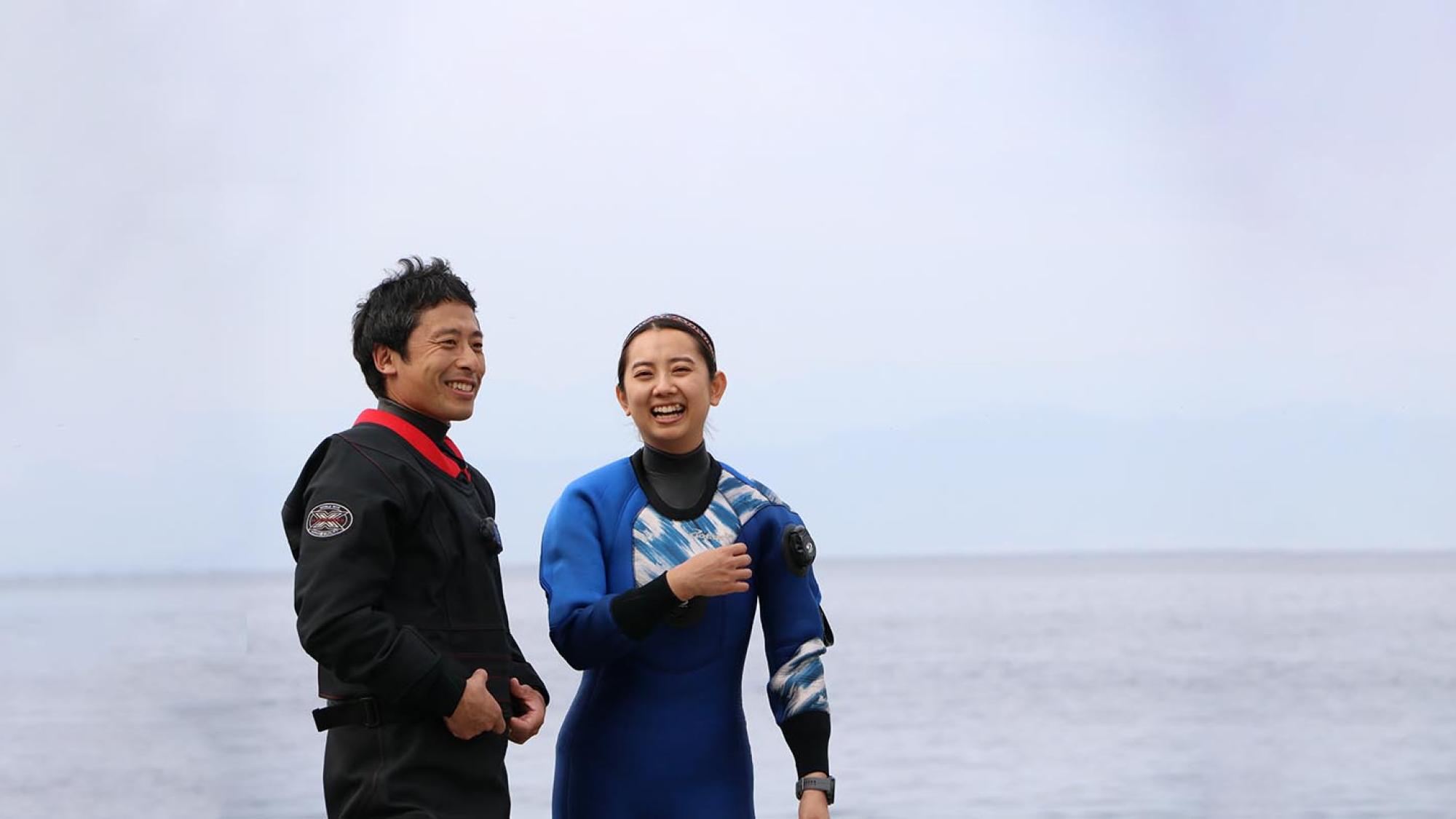 海辺でドライスーツを着て談笑するダイバー