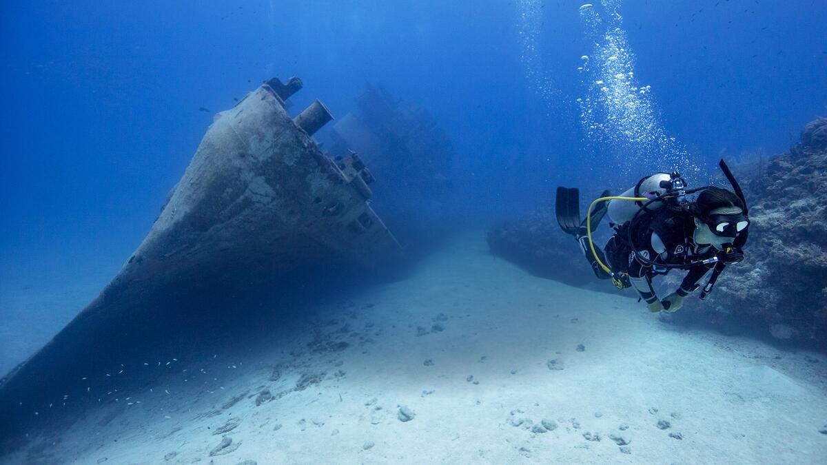 diver diving along ship wreck